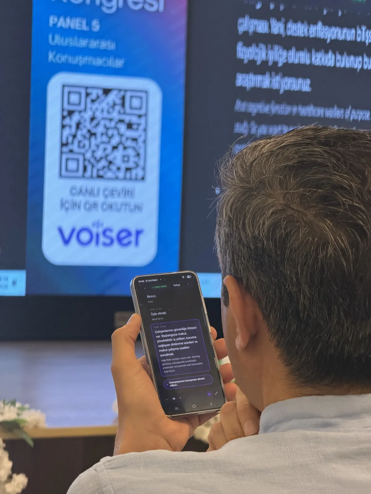 Attendees following the live translation on their phones in the hall
